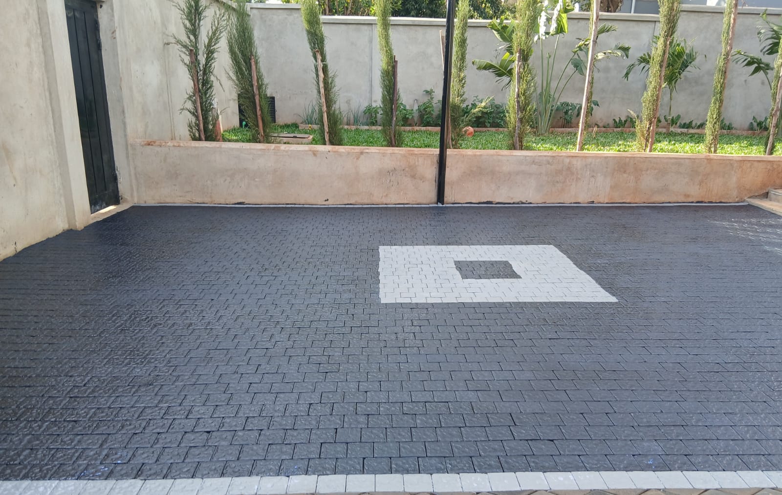 square-cobbles-driveway-cabro-blocks-kenya.jpg Square cobbles paving blocks on a modern black driveway with white centre pattern – Cabro Blocks Kenya